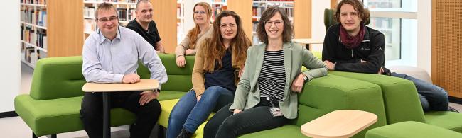 Fünf Personen sitzen auf einem grünen Sofa